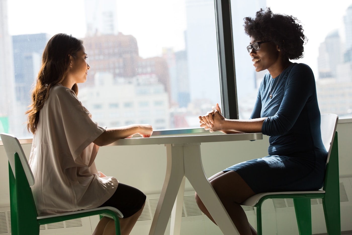 Deux décideuses en pleine discussion devant une vue sur la ville